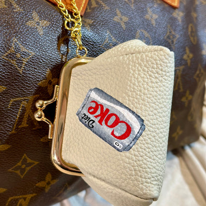Small cream-colored purse with a Kool-Aid logo attached to a patterned bag.