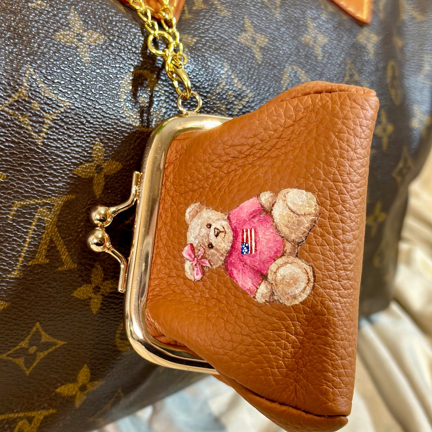 Brown leather pouch with embroidered bear design on a patterned surface
