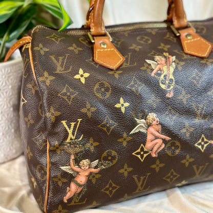 Designer handbag with monogram pattern and cherub designs on a neutral background