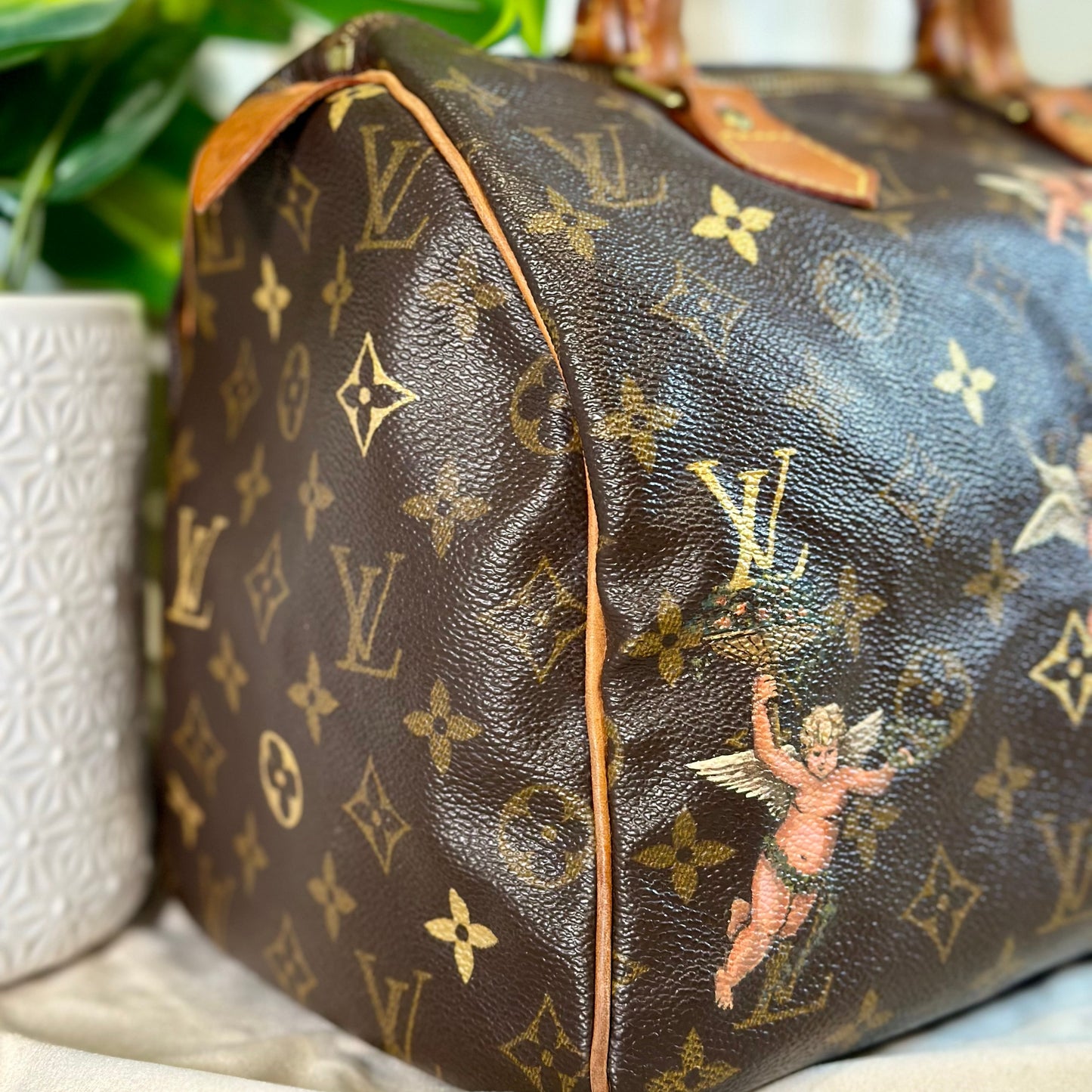 Designer handbag with monogram pattern on a surface with plants in the background