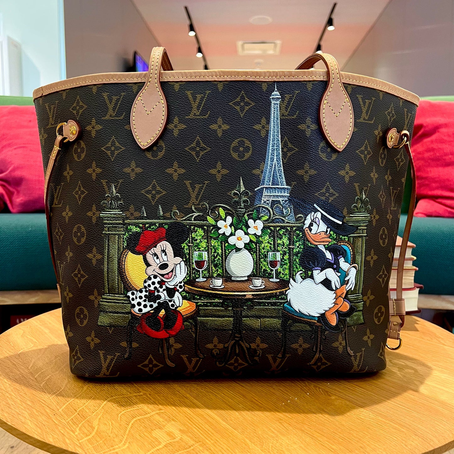 Designer handbag with cartoon characters and scenic design on a wooden table.