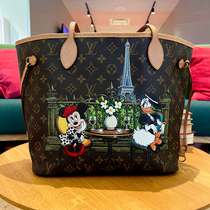 Designer handbag with cartoon characters and scenic design on a wooden table.