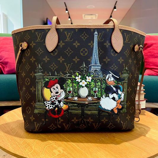 Designer handbag with cartoon characters and scenic design on a wooden table.