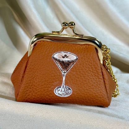 Brown purse with a gold clasp and chain on a beige fabric background