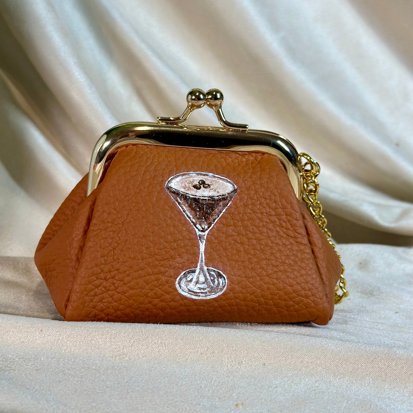 Brown purse with a martini glass design on a beige fabric background