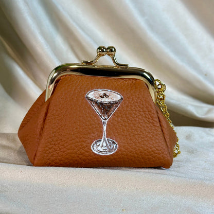 Brown purse with a martini glass design on a beige fabric background