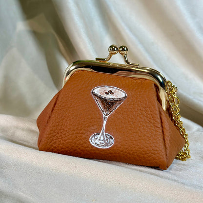 Brown purse with a martini glass design on a beige fabric background
