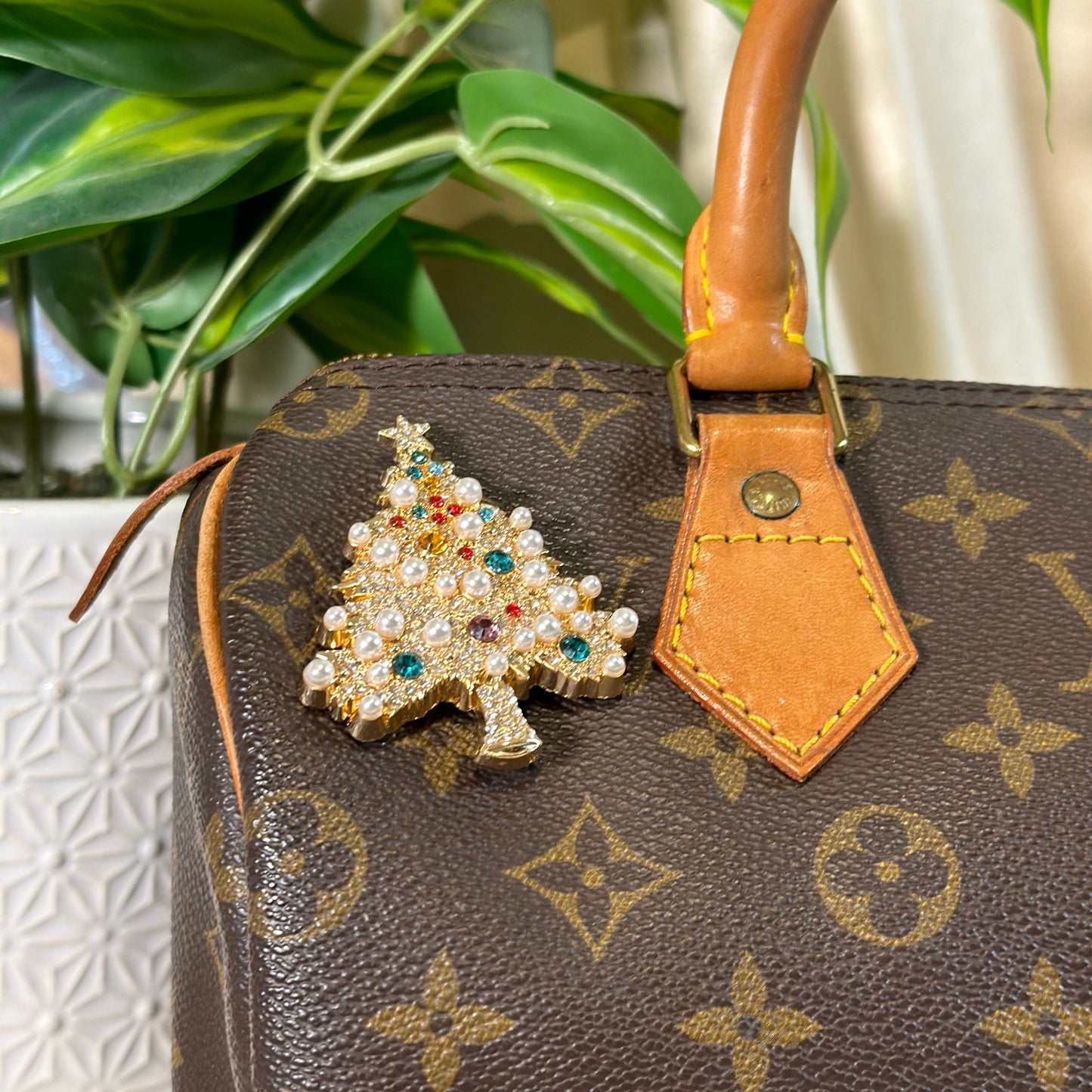 Louis Vuitton handbag with a decorative brooch on a blurred background