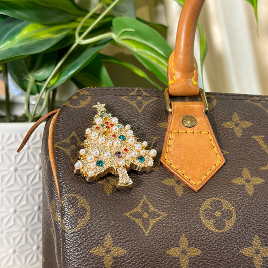 Louis Vuitton handbag with a decorative brooch on a blurred background
