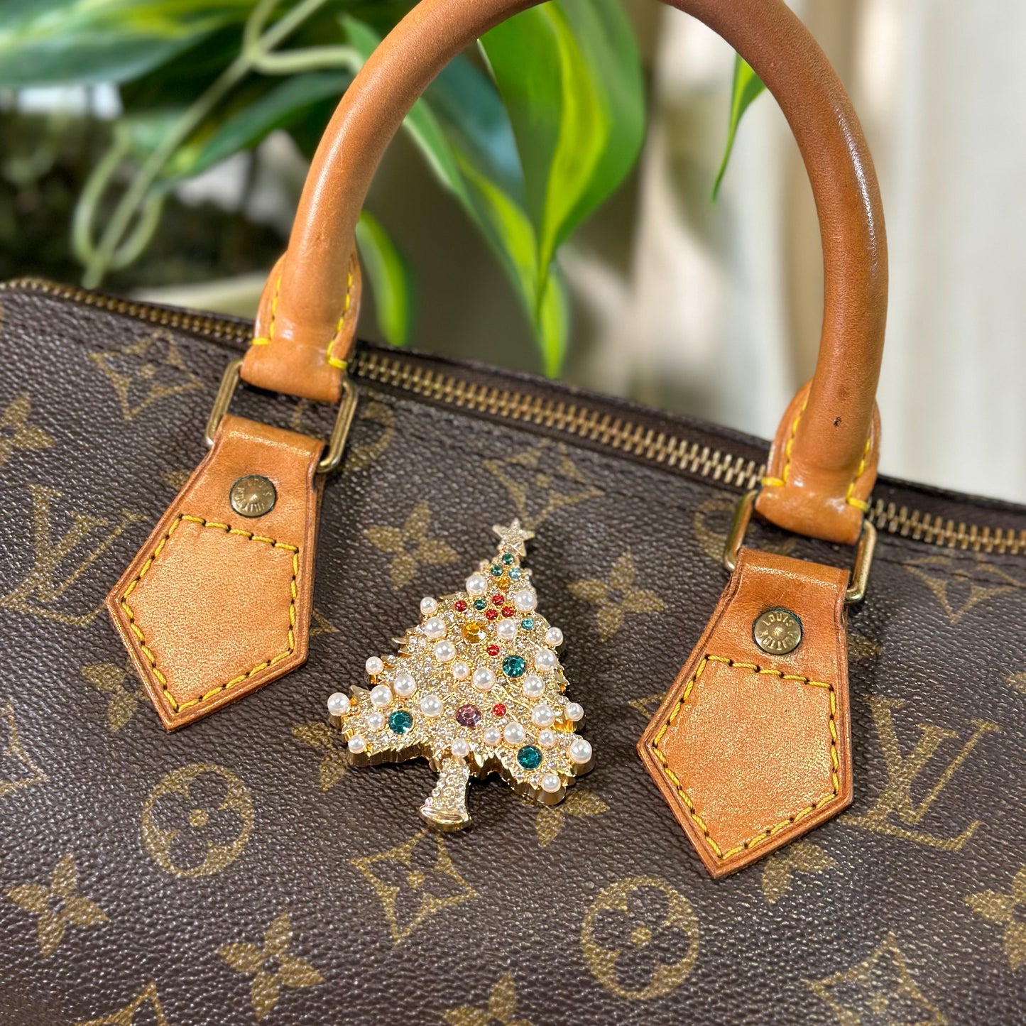 Brown handbag with a decorative Christmas tree charm on a patterned background