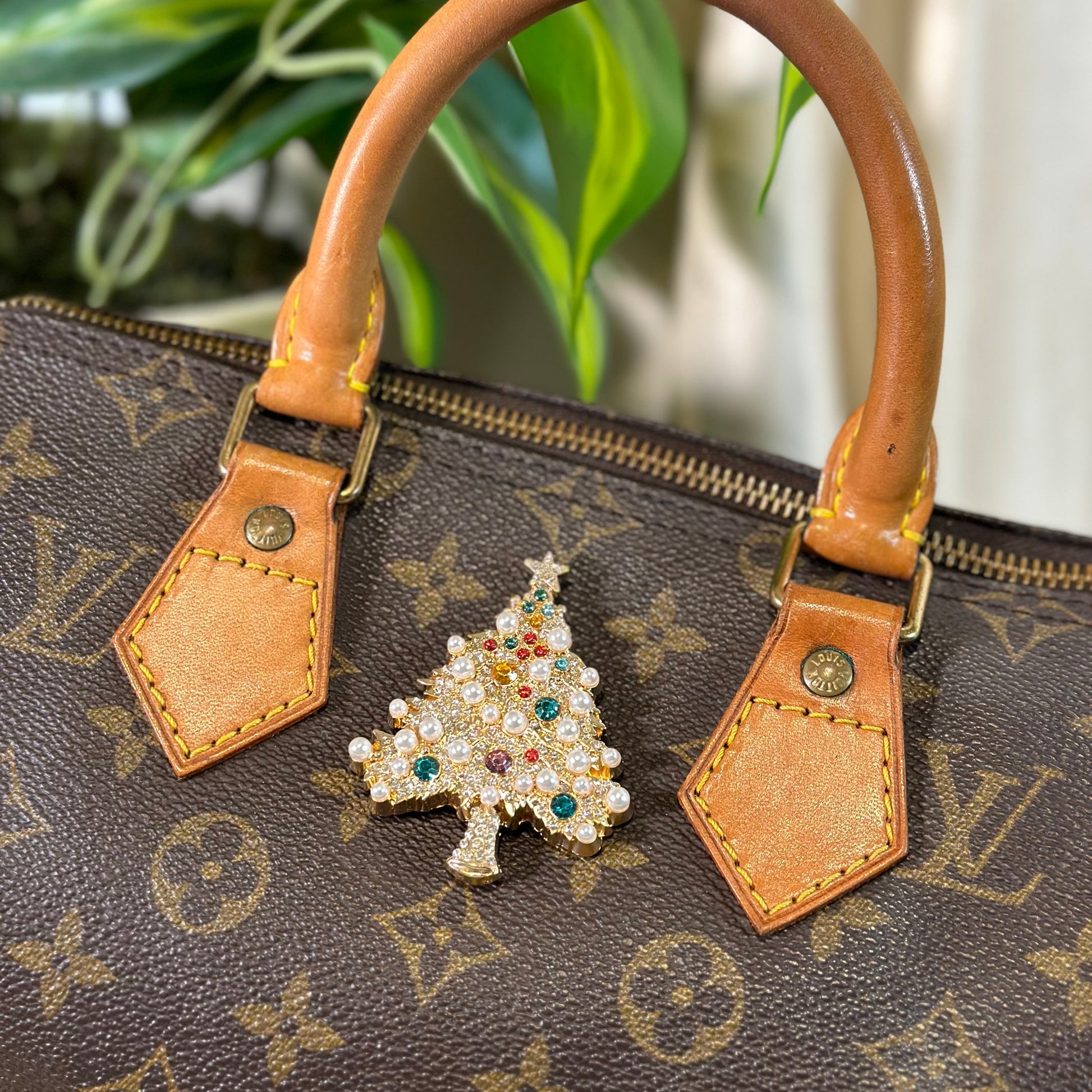 Brown handbag with a decorative Christmas tree charm on a patterned background