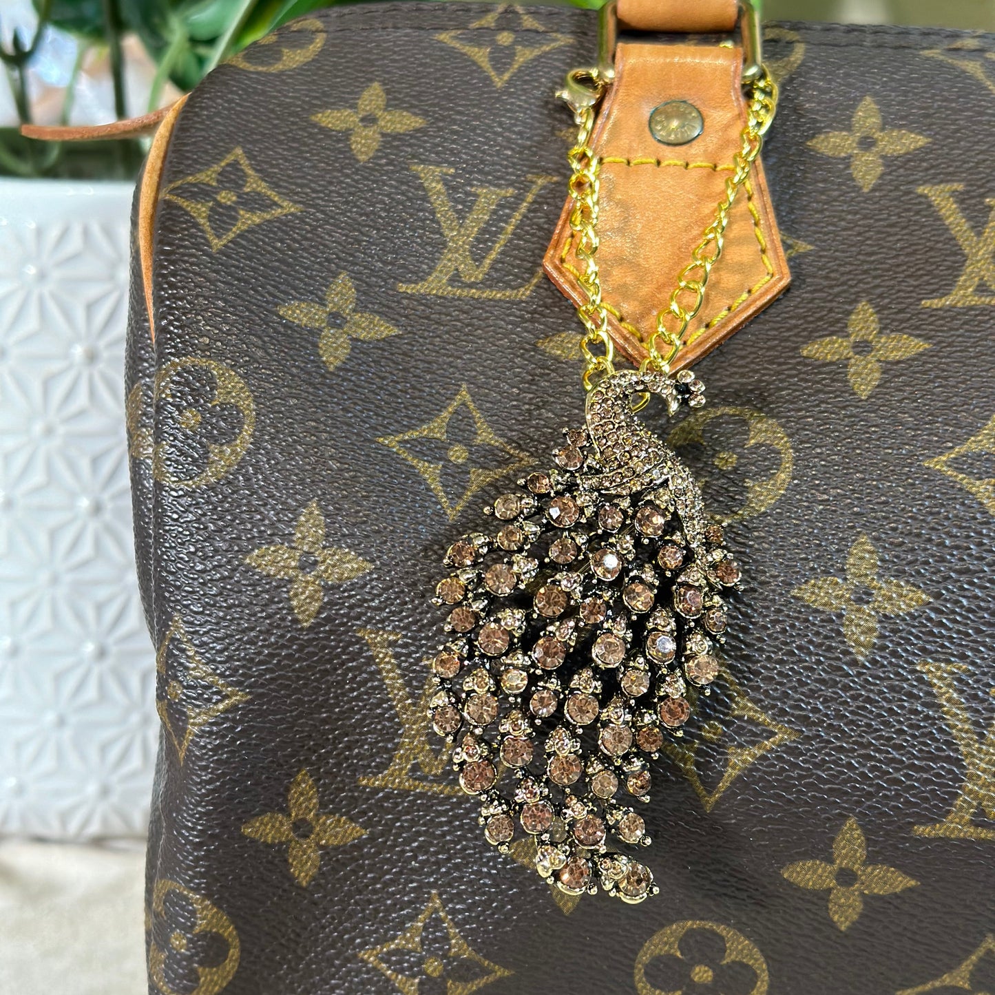 Designer handbag with decorative brooch on a neutral background
