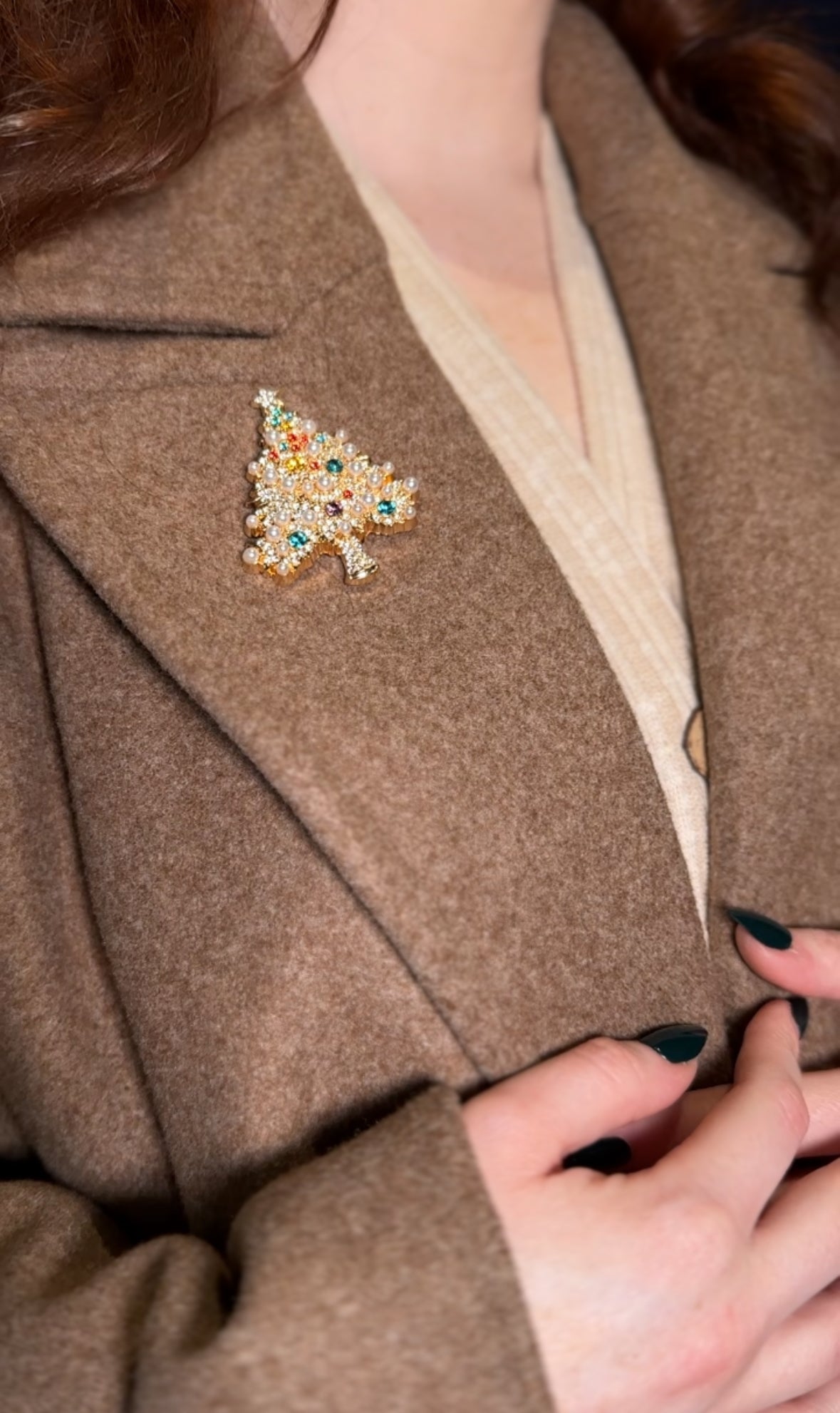 Close-up of a person wearing a brown coat with a decorative brooch.