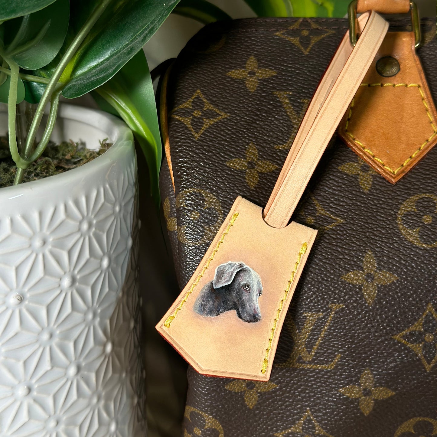 Louis Vuitton handbag with a personalized dog tag featuring a dachshund illustration.