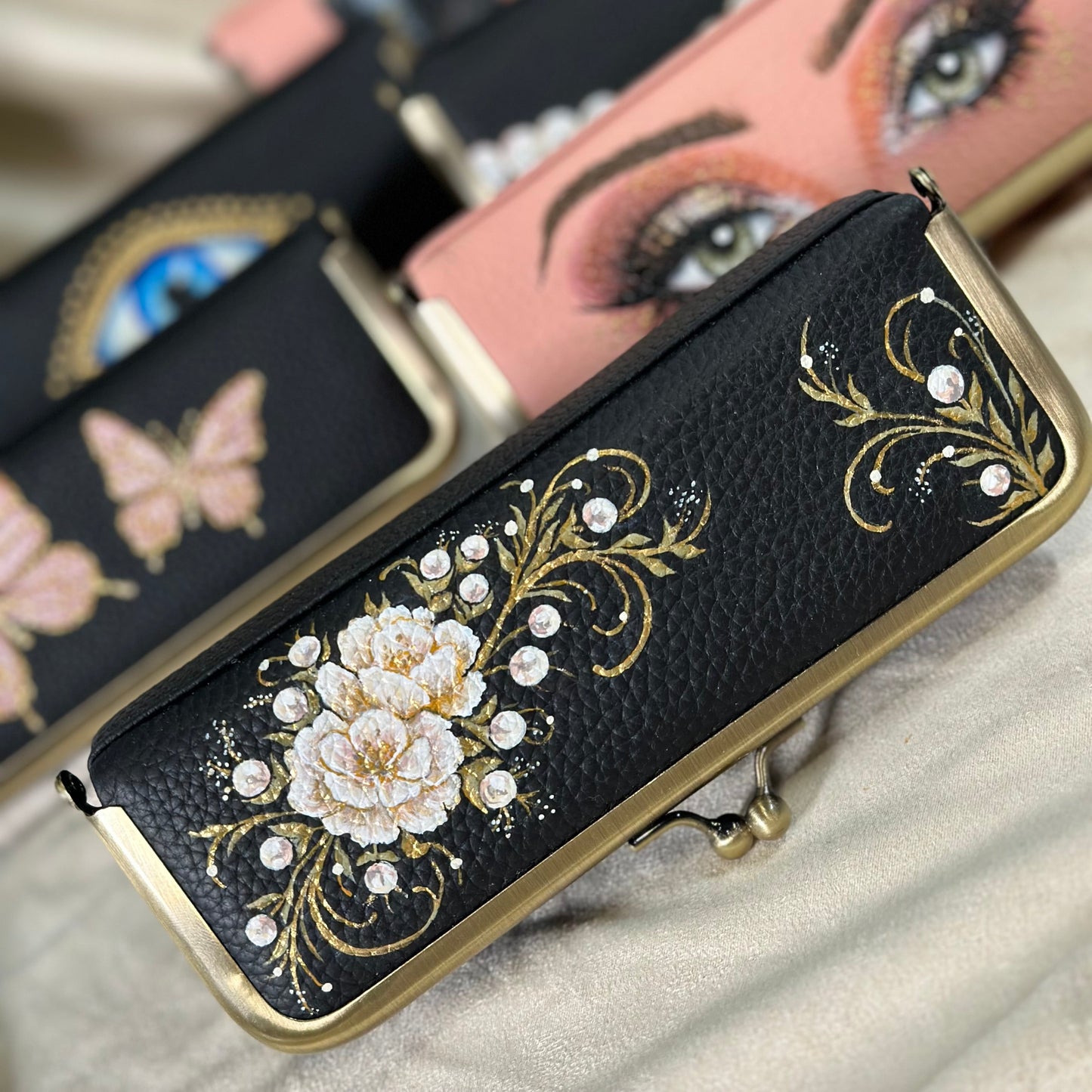 Decorative black clutch with floral design and gold accents on a satin surface.