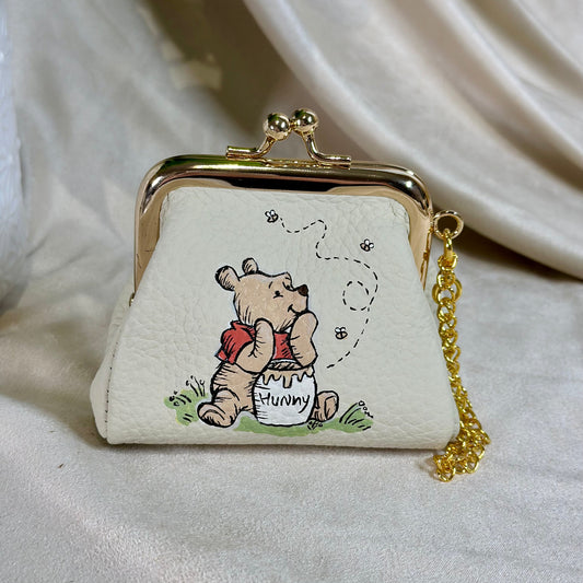 Small white purse with a cartoon character and gold chain on a light background