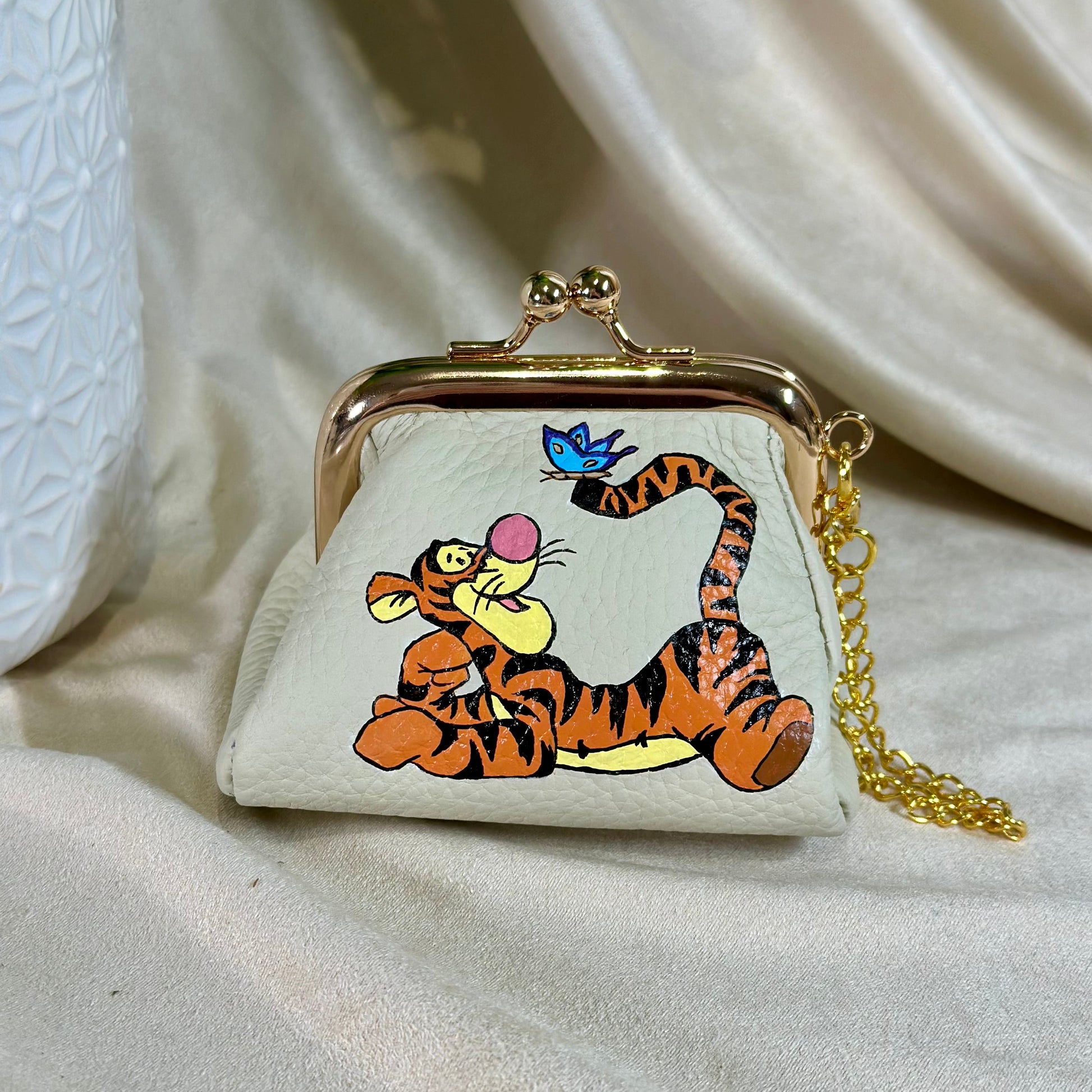 Small purse with cartoon tiger design on a beige fabric background