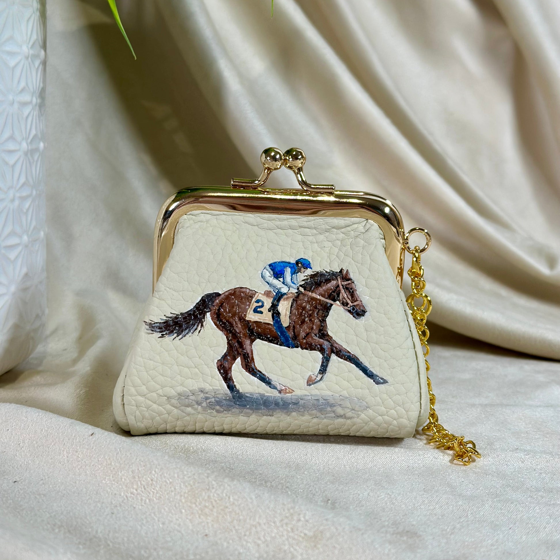Small purse with a horse and jockey design on a beige fabric background