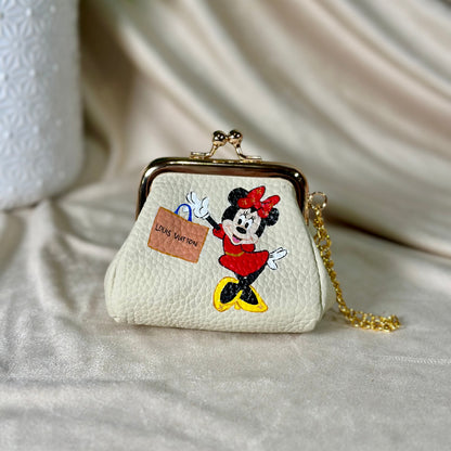 Small white purse with a cartoon character design on a light fabric background