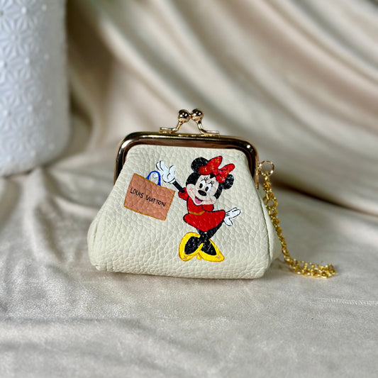 Small white purse with a cartoon character design on a light fabric background