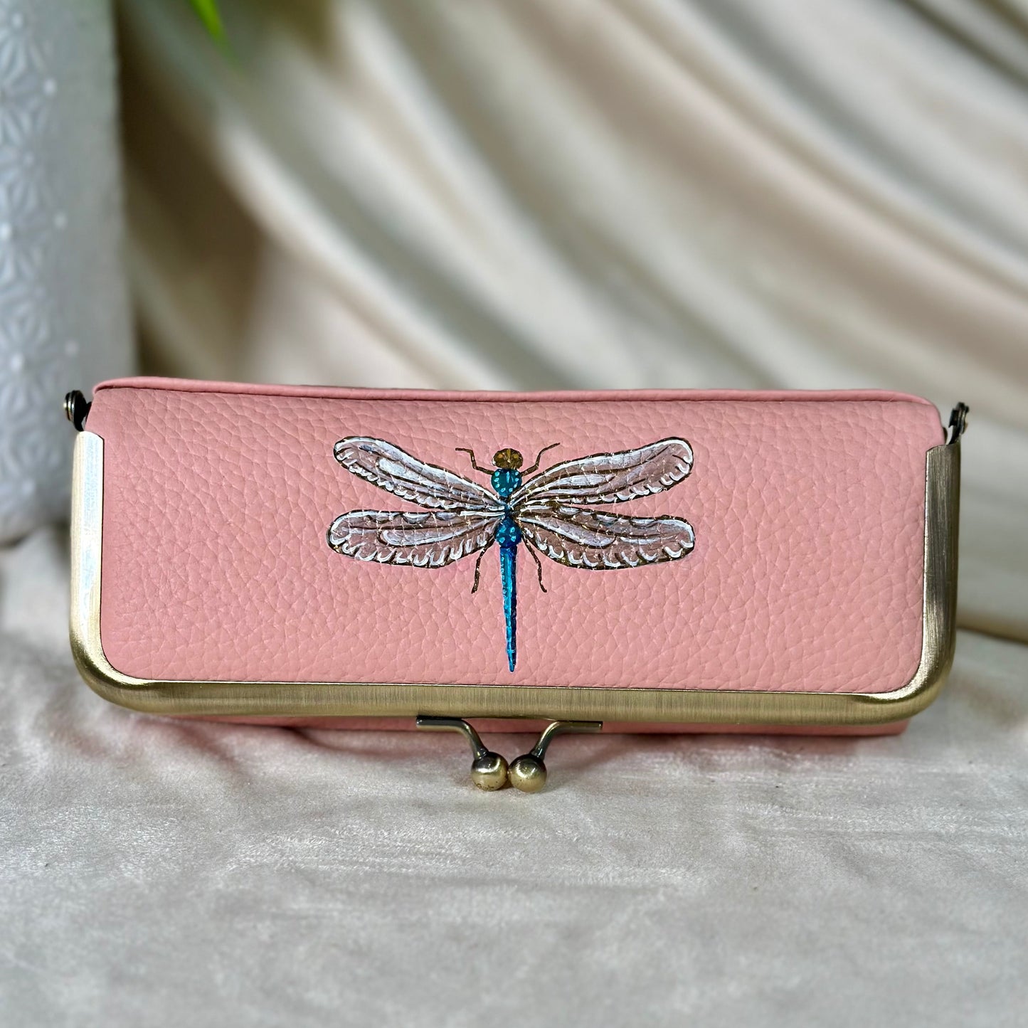 Pink clutch with dragonfly design on a light background