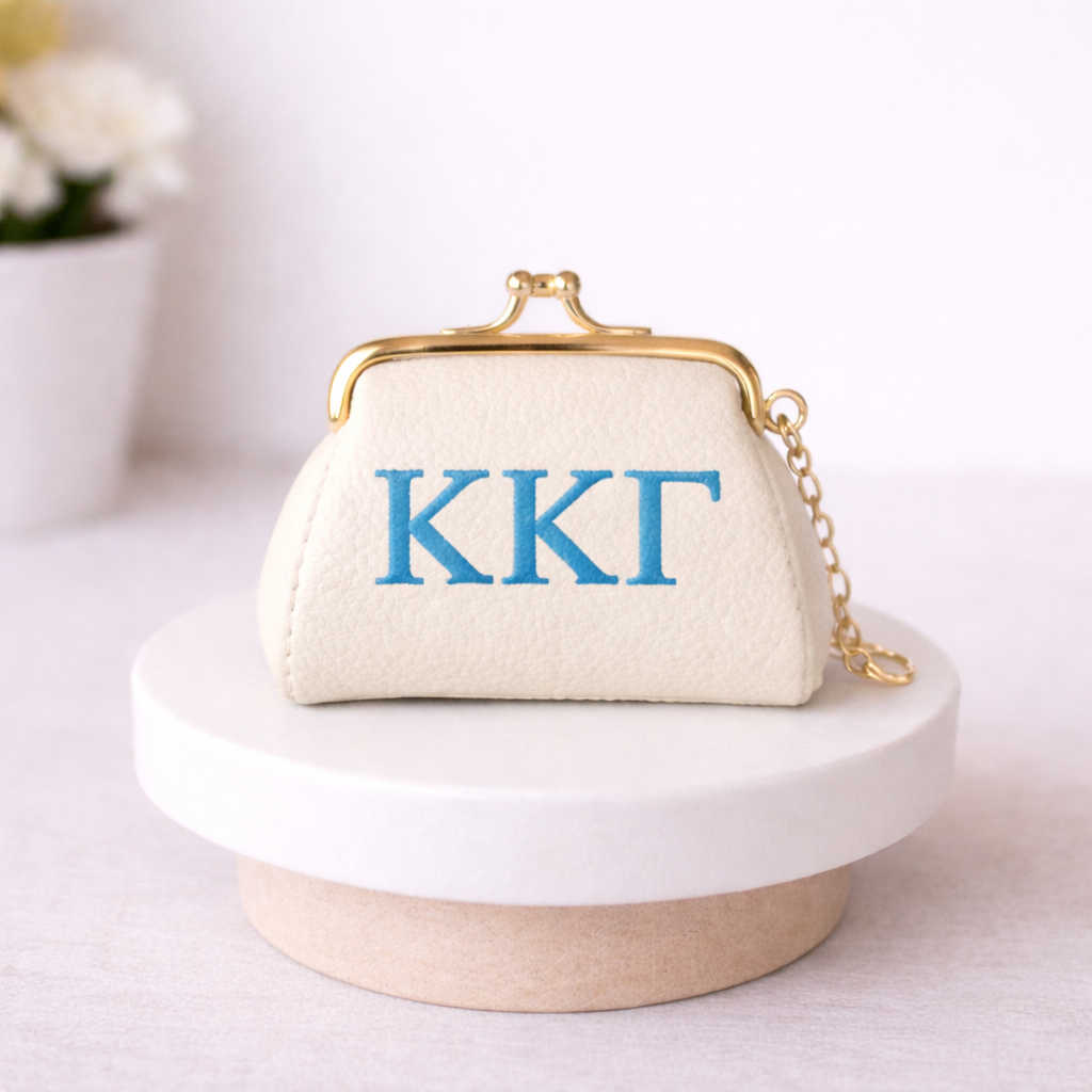 Small cream-colored bag with Kappa Kappa Gamma blue letters on a white surface.