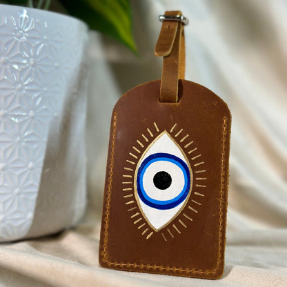 Brown leather luggage tag with eye design on a neutral background