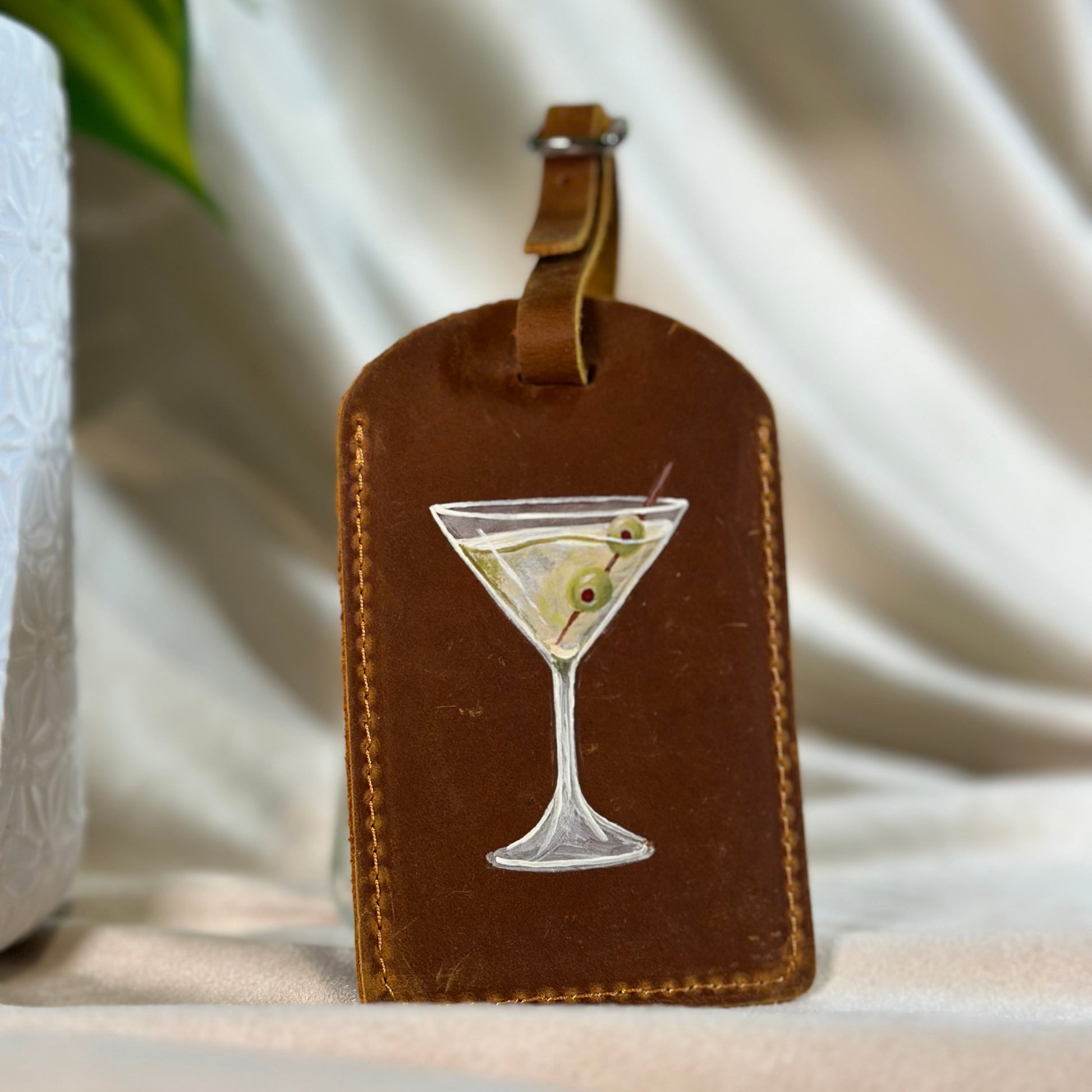 Brown leather luggage tag with a martini glass design on a neutral background
