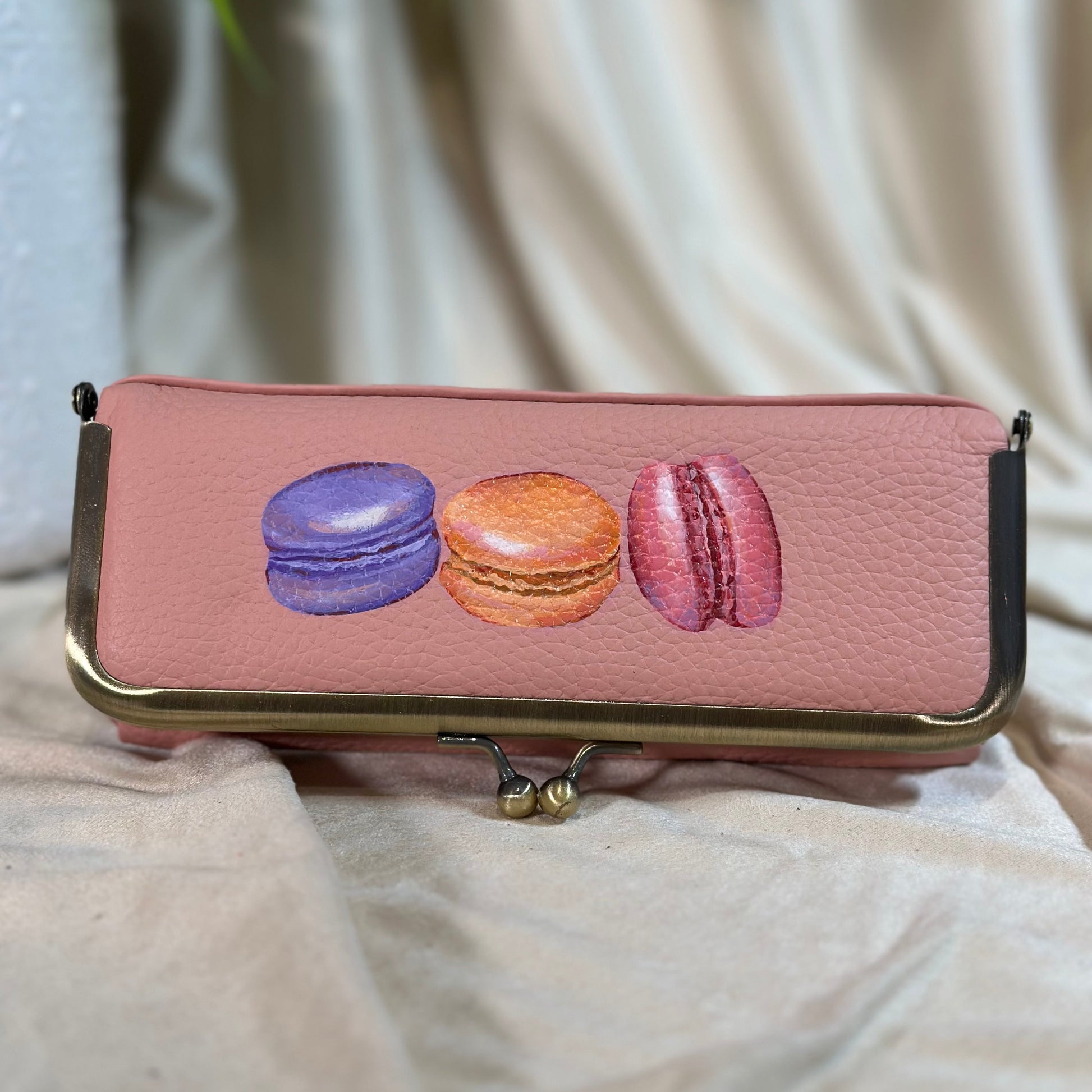 Pink clutch with macaron designs on a beige fabric background