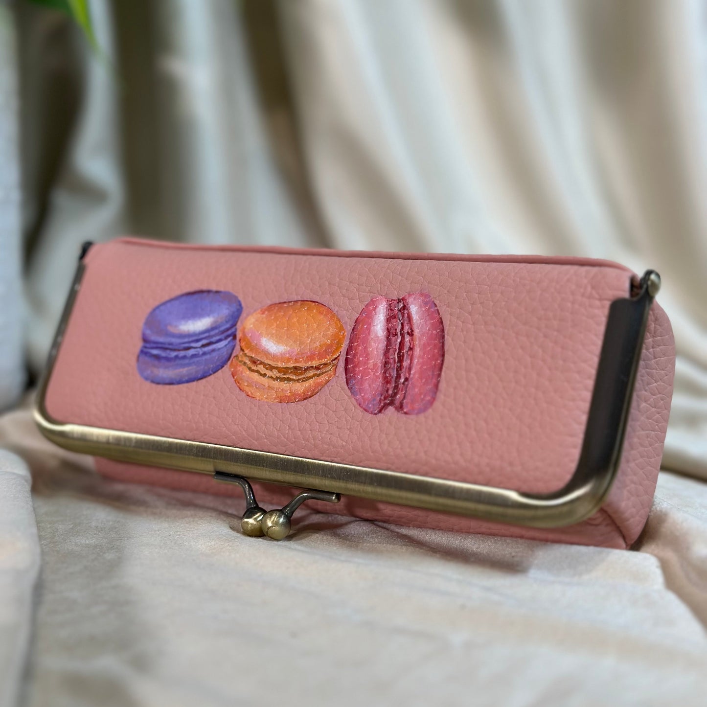 Pink wallet with macaron designs on a light background