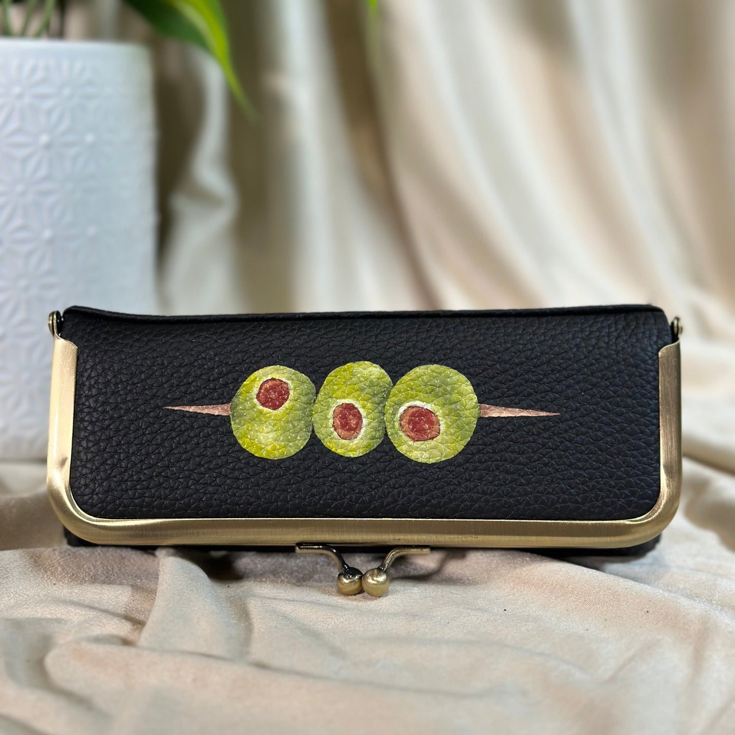 Black clutch with avocado design on a light fabric background