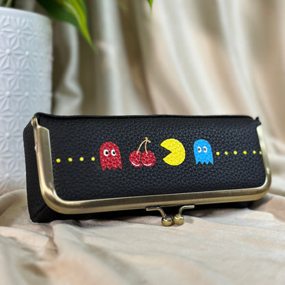 Black clutch with colorful character designs on a light fabric background