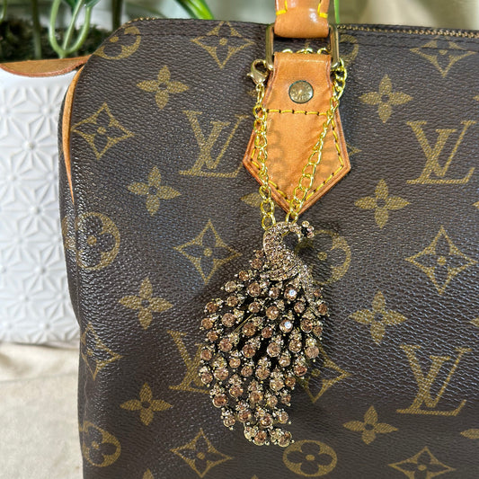 Designer handbag with decorative tassel on a neutral background