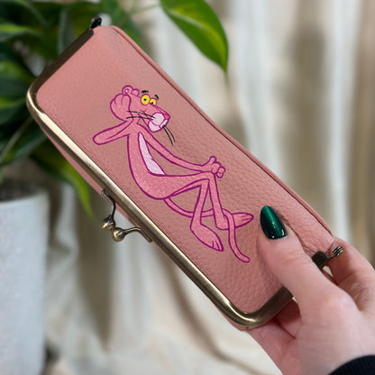 Pink wallet with cartoon character held by a hand against a neutral background