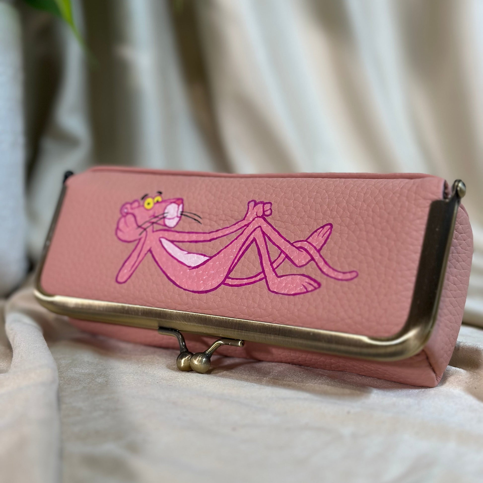 Pink wallet with a character design on a light background