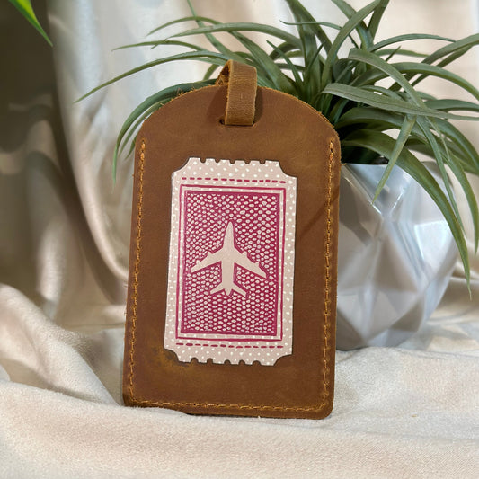 Brown leather luggage tag with airplane design on a white background