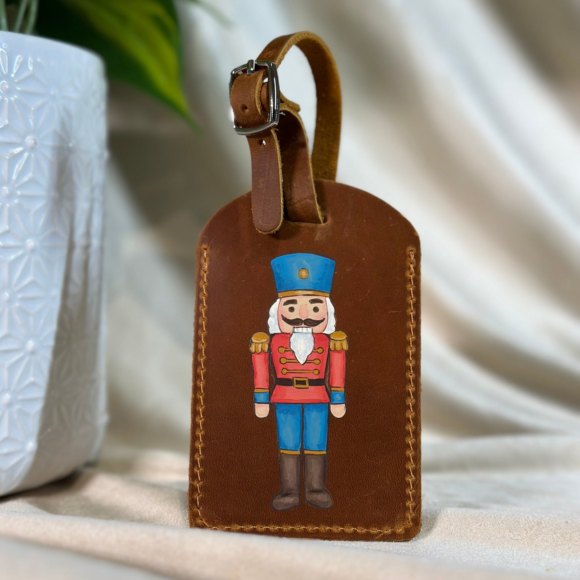 Brown leather luggage tag with nutcracker design on a light background