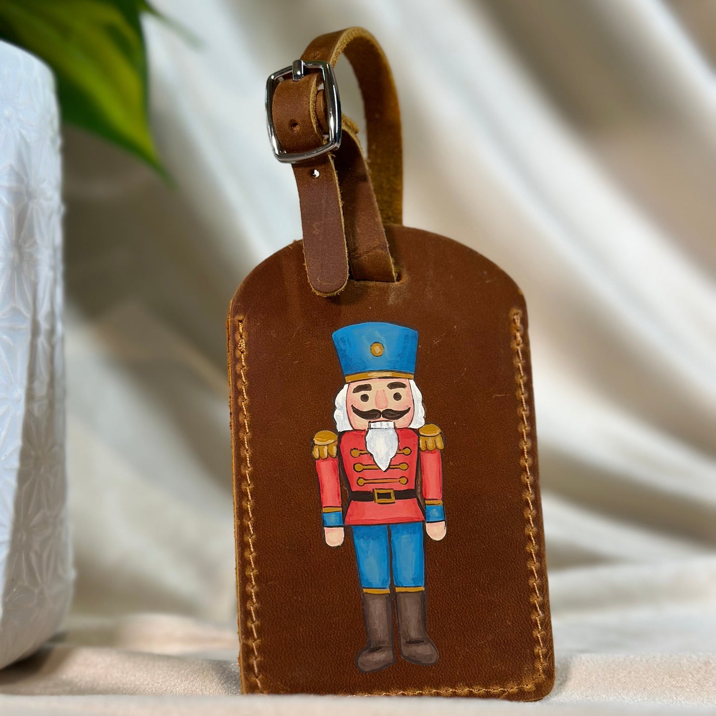 Brown leather luggage tag with a nutcracker design on a neutral background