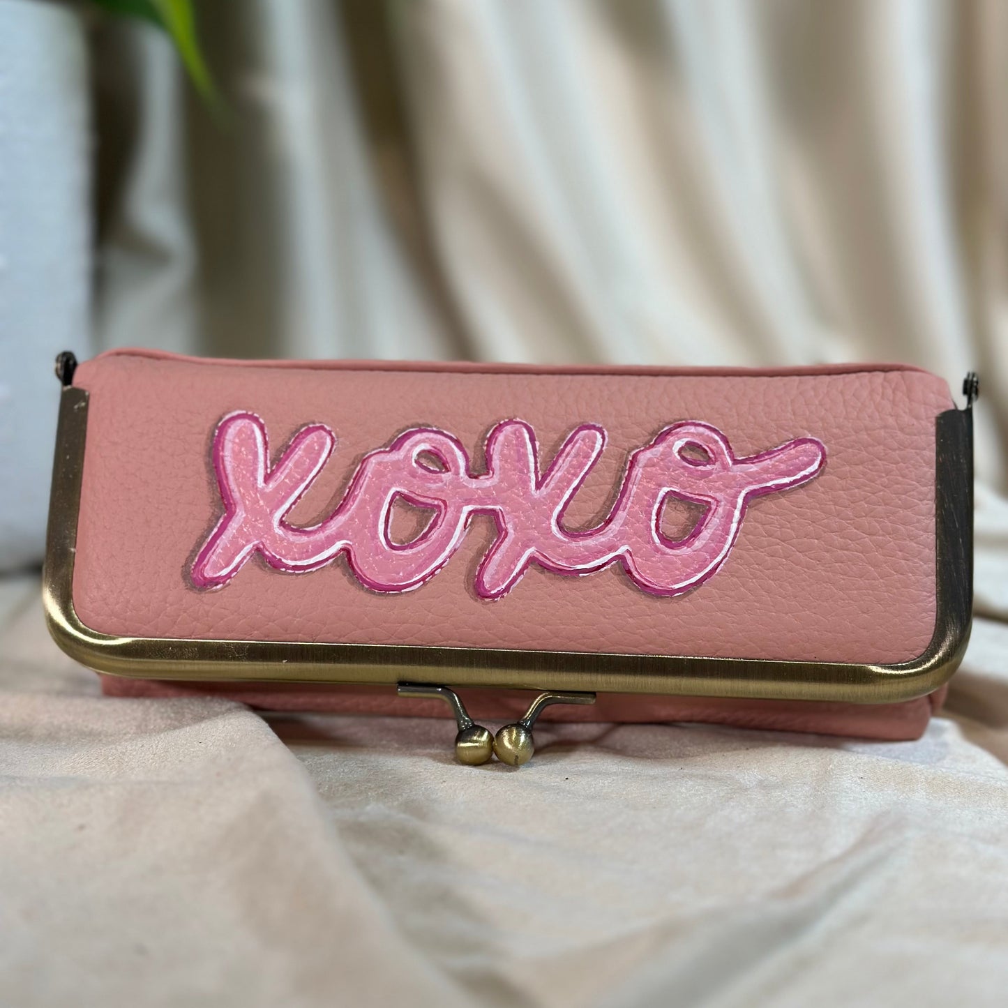 Pink pouch with 'xoxo' embroidery on a light background