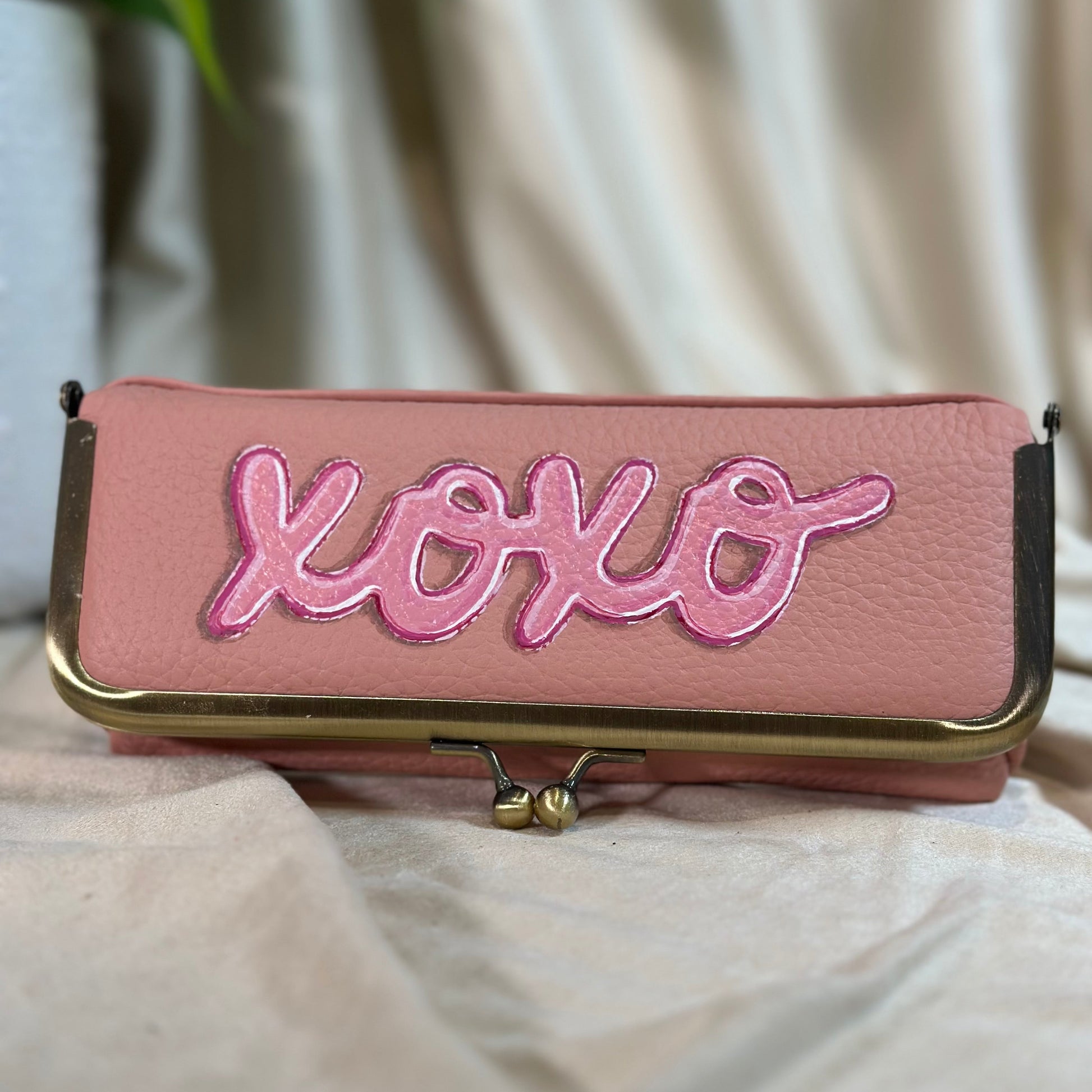 Pink pouch with 'xoxo' embroidery on a light background