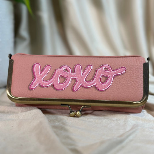 Pink pouch with 'xoxo' embroidery on a light background