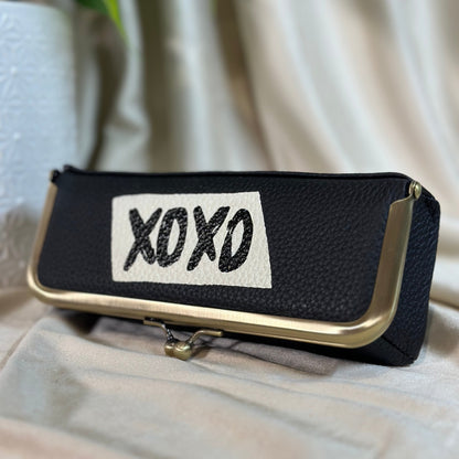 Black clutch with 'XOXO' label on a light surface