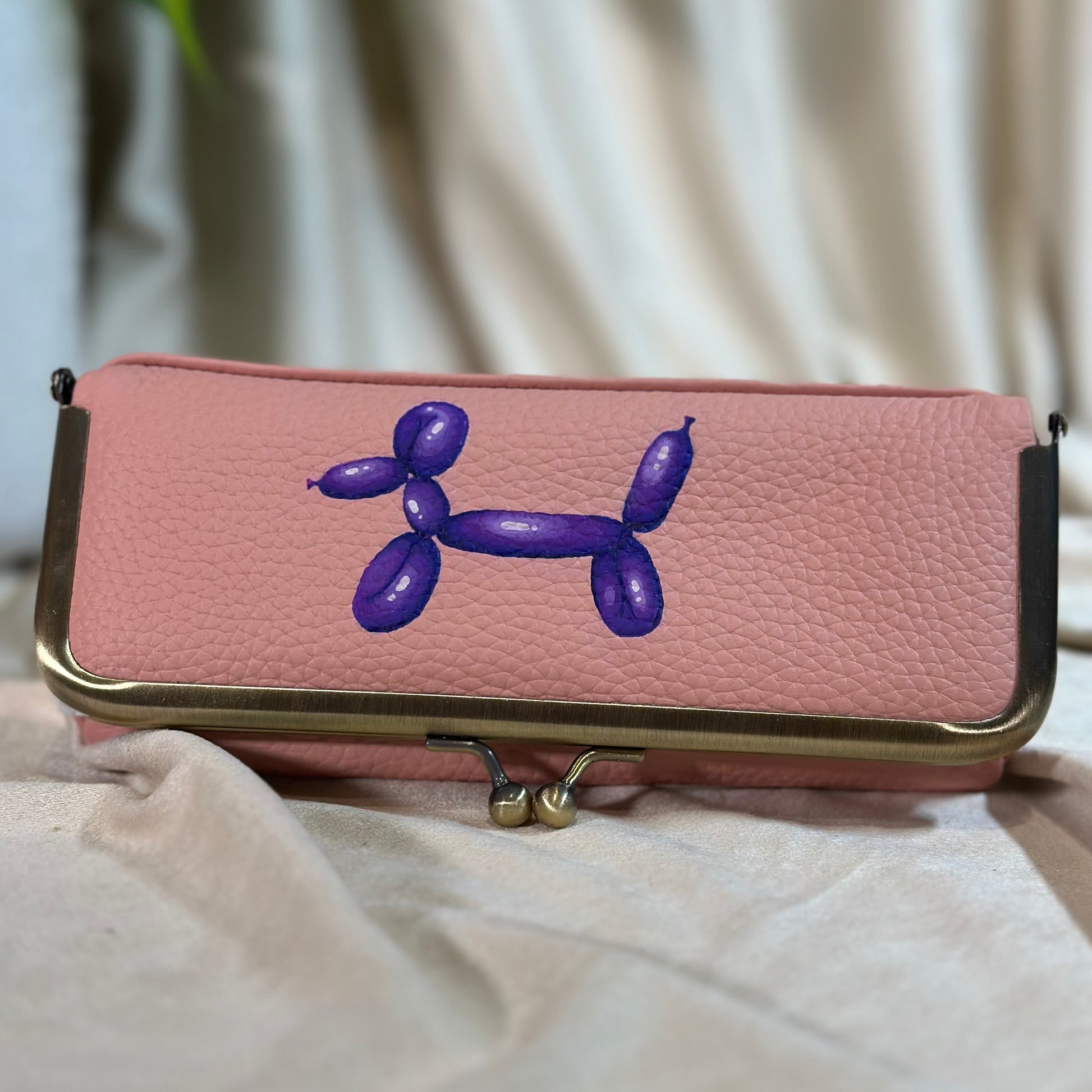 Pink phone case with a purple balloon dog design on a light background