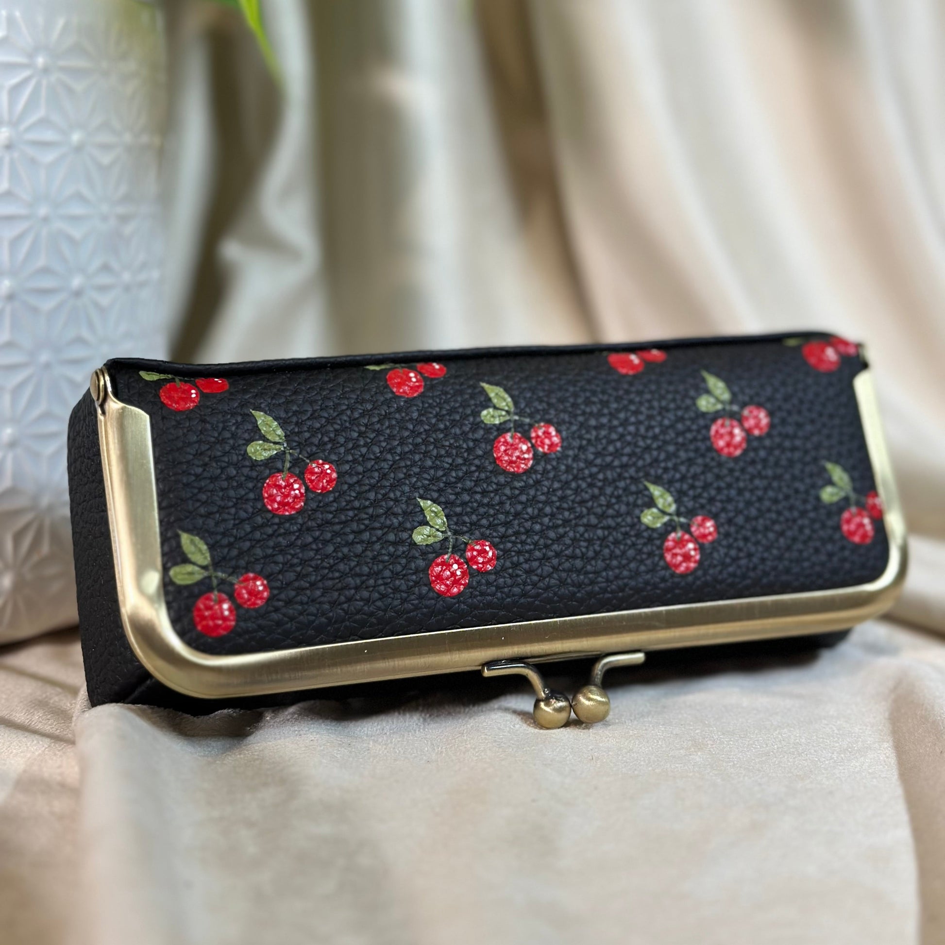Black clutch with red cherry pattern on a light background
