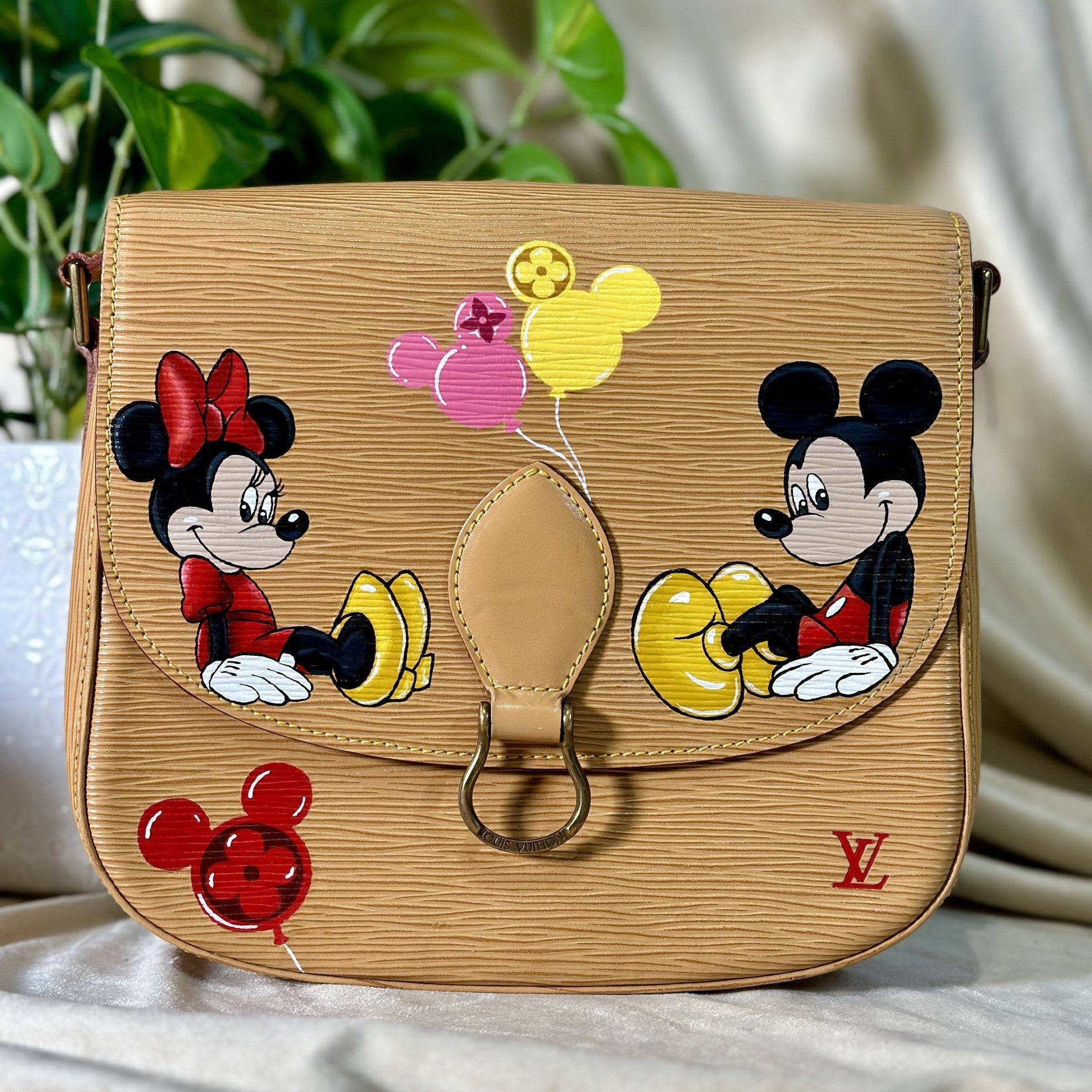 Designer handbag with cartoon characters and balloons on a neutral background