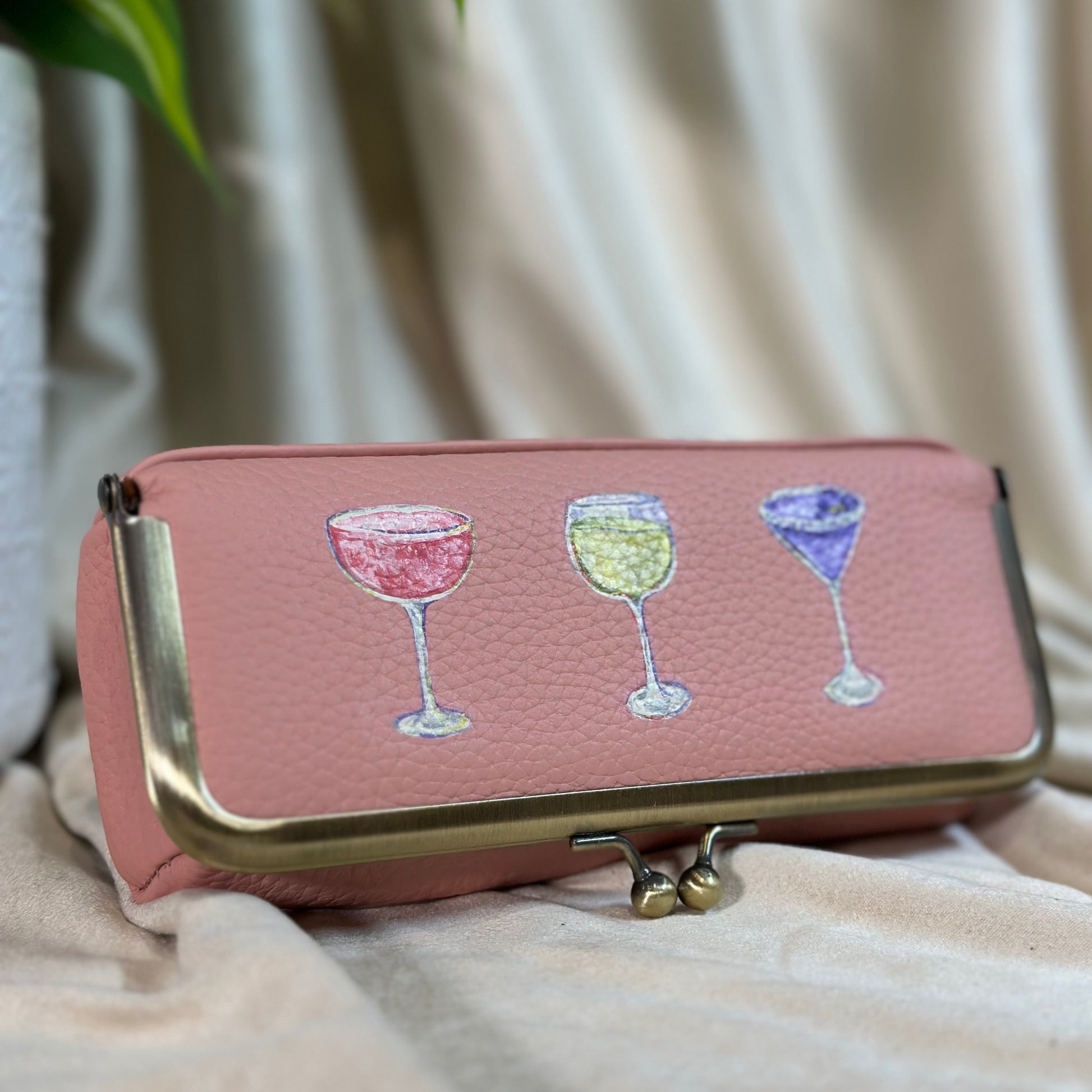 Pink wallet with wine glass illustrations on a beige surface