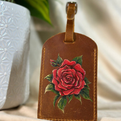 Brown leather luggage tag with a red rose design on a neutral background
