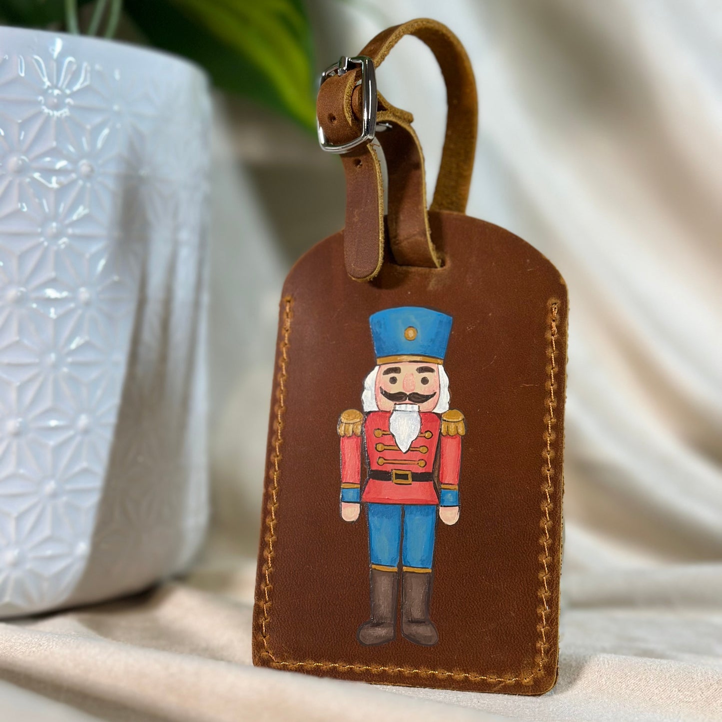Brown leather luggage tag with nutcracker design on a neutral background