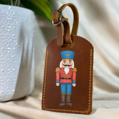 Brown leather luggage tag with nutcracker design on a neutral background
